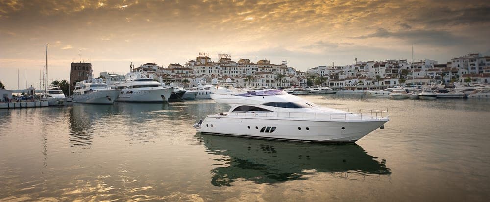 Yate a motor blanco atracado en un puerto deportivo al atardecer