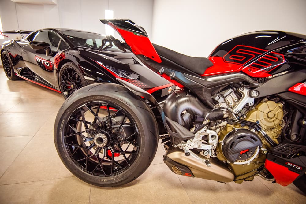 Ducati Streetfighter V4 negra y roja, con un Lamborghini Huracán STO al fondo.