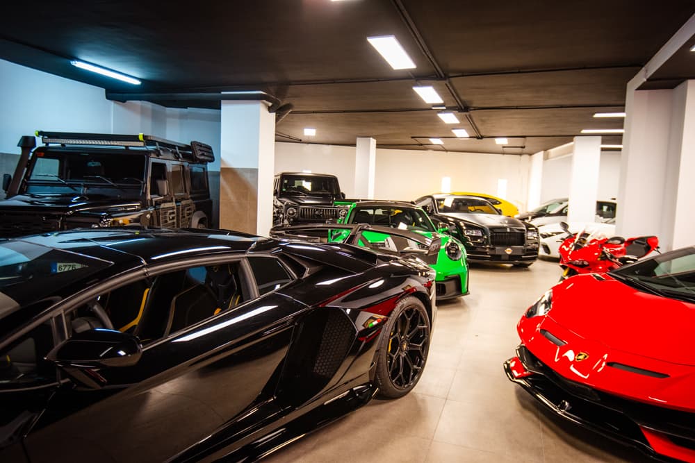 Interior de nuestro salón: un Lamborghini negro y otro rojo en primer plano, y más coches y una moto al fondo.